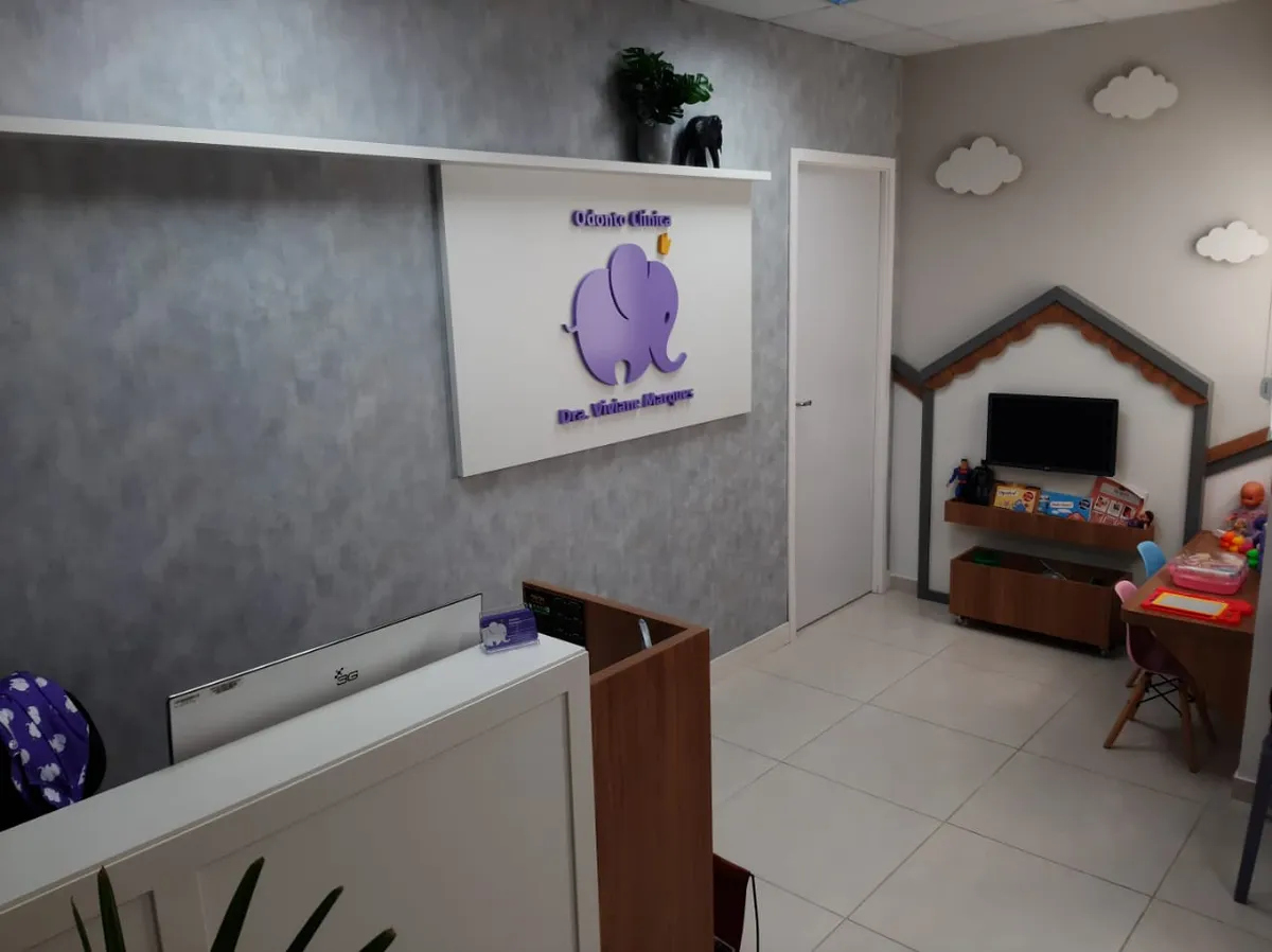 Recepção com o elefante do logo na parede e o espaço kids em forma de casinha ao fundo